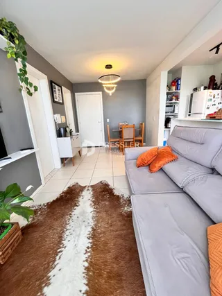A sala de estar apresenta um sofá cinza e um tapete marrom.