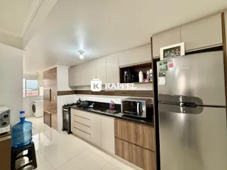 Cozinha moderna com armários brancos e bancadas escuras.