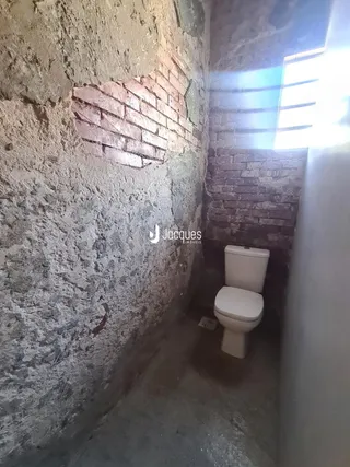 Vista de um corredor estreito com paredes de alvenaria rústica