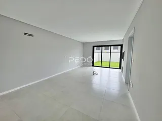 Ambiente interno de uma sala longa com paredes brancas e piso claro.