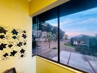 A vista da janela mostra uma rua e vegetação ao ar livre.