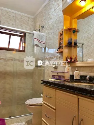 Foto de um banheiro com revestimento de azulejos e box de vidro.