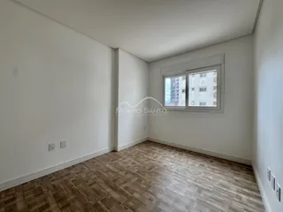 Ambiente interno de uma sala com piso de madeira e janela para a cidade.