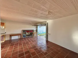 Sala de estar com piso de tijolos vermelhos e paredes brancas.