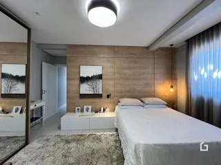 Quarto com cama e parede de madeira clara.