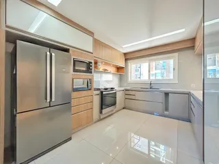 Vista da cozinha moderna com armários de madeira e eletrodomésticos de aço inoxidável.