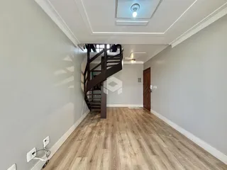 Hall de entrada com escada de madeira e piso de madeira clara.