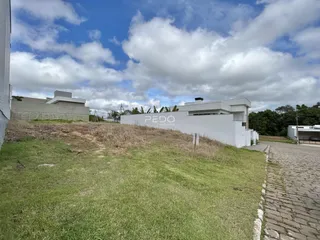 Vista externa de uma propriedade com gramado e muro branco.