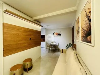 Sala de estar com painel de madeira e sofá claro em um imóvel no Brasil.