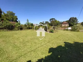 Vista externa de um terreno com gramado verde sob céu azul.
