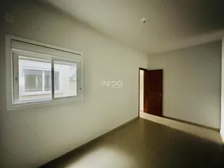 Vista interna de um corredor com janela e porta em uma residência.