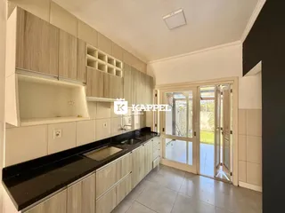 A cozinha moderna apresenta armários em tons neutros e uma bancada escura.