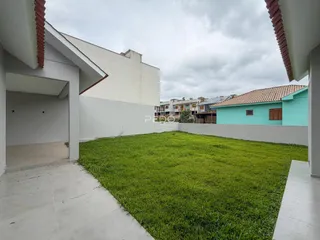 Vista externa de um terreno gramado com uma casa branca.