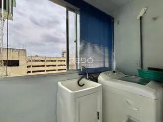 Vista interna de um cômodo com janela e máquina de lavar roupa.