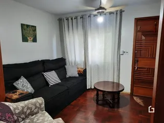 Sala de estar com sofá escuro e piso de madeira.
