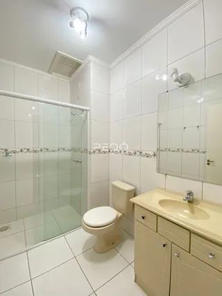 Foto de um banheiro com revestimento cerâmico branco e box de vidro.