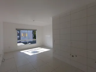 Interior de uma sala de estar clara com piso de cerâmica e grande janela.
