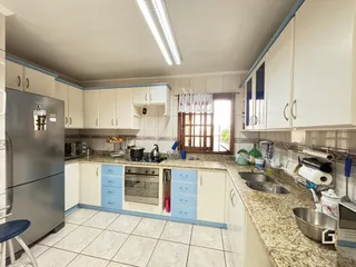Uma cozinha com armários brancos e bancada de granito.