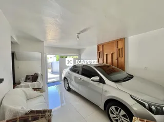 Uma sala de estar clara com sofá branco e piso de cerâmica.