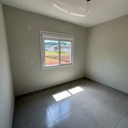 Vista interna de um cômodo com piso de cerâmica e janela.