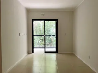 Hall de entrada com porta de vidro voltada para a natureza.