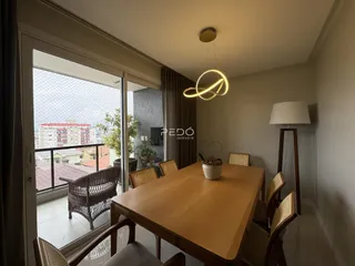Ambiente interno com mesa de jantar de madeira e vista para o exterior.