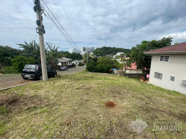 Vista externa de um terreno gramado com vegetação ao fundo.