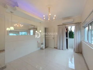 Sala de estar com piso de cerâmica clara e paredes brancas.