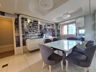 Ambiente interno de uma sala de jantar com decoração moderna e vista para uma paisagem urbana.