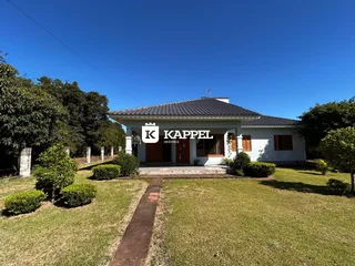 Fachada de uma casa em Lajeado, Brasil, com jardim gramado e céu azul.