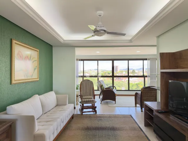 Sala de estar com sofá branco e vista panorâmica da cidade.