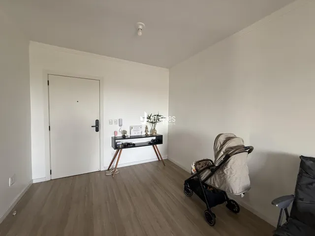Ambiente interno de uma sala com piso de madeira clara e porta branca.