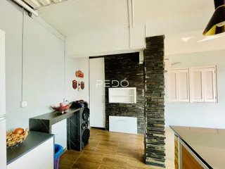 Interior de uma sala de estar com parede de pedra e piso de madeira.
