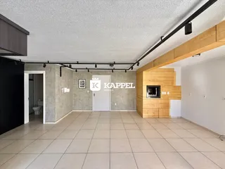 Uma sala de estar ampla com piso de cerâmica e parede de madeira.