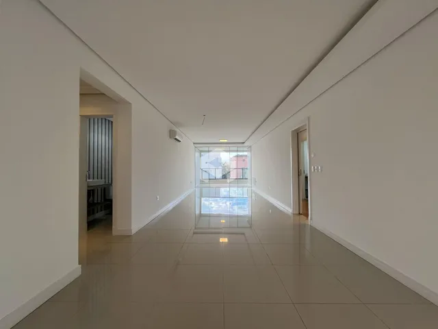 Corredor interno de uma residência com piso de cerâmica clara.