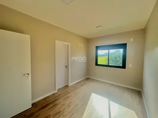Ambiente interno de uma sala com piso de madeira clara e janela para a paisagem.