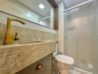Banheiro com bancada de mármore e louças brancas.