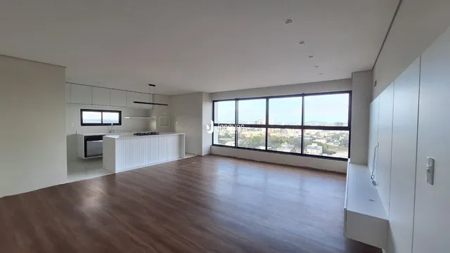 Sala de estar com piso de madeira e cozinha moderna em um apartamento.