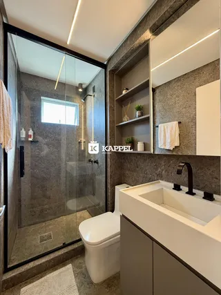 Banheiro moderno com box de vidro e bancada de mármore.