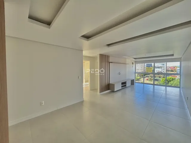 Sala de estar ampla com piso de cerâmica e grande porta de vidro.