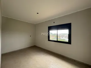 Ambiente interno de uma sala vazia com piso de cerâmica e janela.