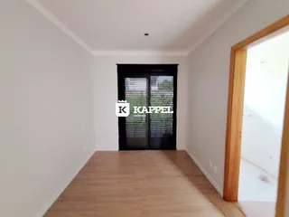 Hall de entrada com piso de madeira e porta escura.