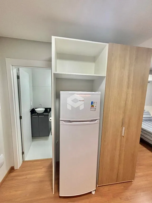 Parede interna mostrando um armário e uma geladeira branca em um ambiente residencial.