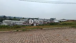 Vista externa de uma propriedade com casas ao fundo e um pátio pavimentado na frente.