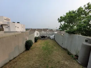 Um quintal gramado é delimitado por muros laterais.