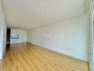 Vista interna de um ambiente com piso de madeira clara.