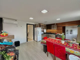 Ambiente interno de sala de estar com cozinha integrada e piso de cerâmica.