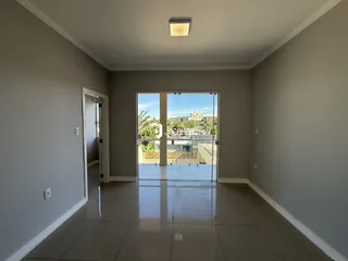 Corredor interno com piso de cerâmica e porta de vidro que dá para a vista.