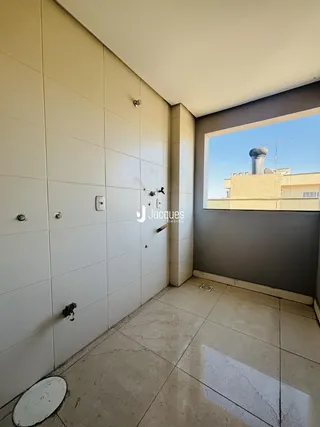Vista de uma parede interna com revestimento cerâmico e piso de concreto em um imóvel.
