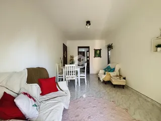 Sala de estar com sofá e mesa de jantar em ambiente claro.